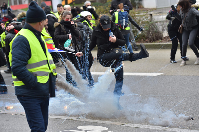 A ‘yellow vest’ anti-government protester kicks a teargas shell during a rally in Nantes, France, on Saturday (AFP photo)