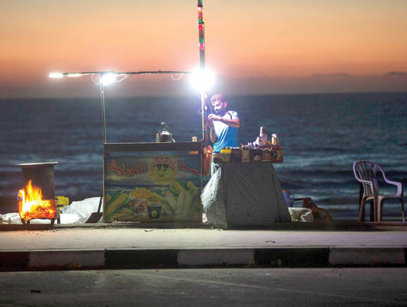 This file photo taken on June 11 shows a Palestinian street vendor standing behind his stall in front of the beach in Gaza City during a power outage. Israel on Monday began reducing electricity supplies to the Gaza Strip, despite warnings the move could increase suffering and tensions in the Palestinian enclave (AFP photo)