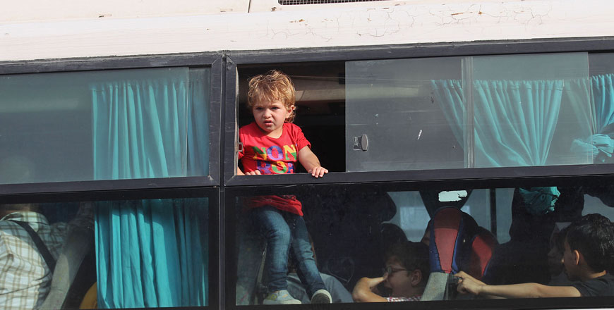 A Palestinian child looks out of a bus window as passengers wait to cross to Egypt at the Rafah border crossing in the southern Gaza Strip, on Tuesday (AFP photo)