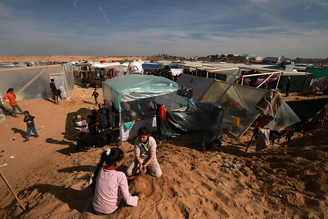 Palestinians children who fled Khan Yunis play atop a pile of sand as others set up camp in Rafah further south near the border with Egypt, on Thursday  (AFP photo)