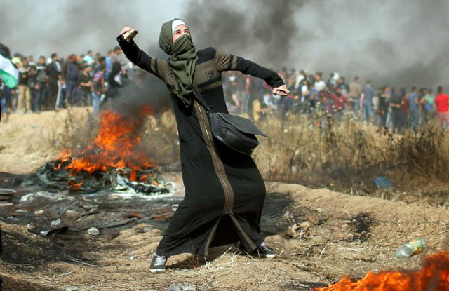 A girl hurls stones during clashes with Israeli forces at a protest where Palestinians demand the right to return to their homeland, at the Israel-Gaza border, east of Gaza City, on April 13, 2018 (Reuters photo)