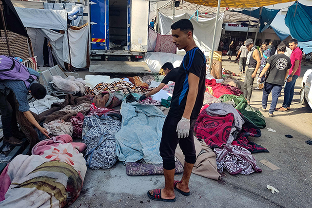 Men check the bodies of people killed in bombardment that hit a school housing displaced Palestinians, as they lie on the ground in the yard of Al Shifa hospital in Gaza City on Friday (AFP photo)