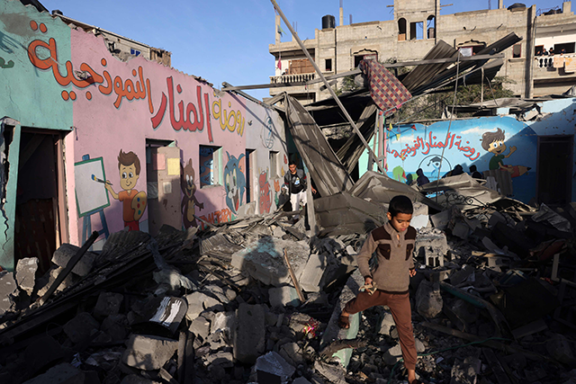Children walk amid the rubble of a school hit during an Israeli strike before the start of a four-day truce in the battles between Israel and Hamas militants, in Rafah in the southern Gaza Strip on Friday (AFP photo)