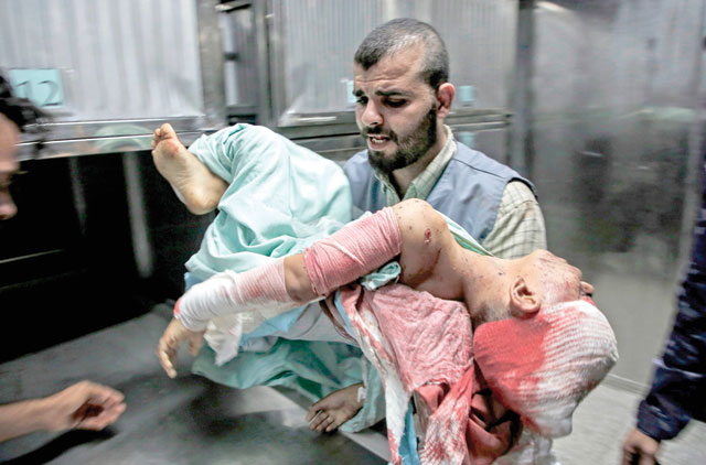  A man carries the body of Amir Ayad, a Palestinian boy who was killed in an Israeli strike on Monday, at the mortuary of Gaza City's Al Shifa Hospital (AFP photo)
