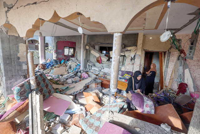 People look for salvageable items in a house damaged during Israeli bombardment in Rafah, on the southern Gaza Strip on Friday (AFP photo)