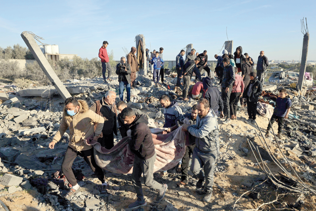 People carry away the body of a victim found under the rubble of a house that was used as a shelter by a displaced Palestinian family, many of whom were reported killed when it was destroyed during an Israeli strike on Rafah in the southern Gaza Strip on Sunday (AFP photo)