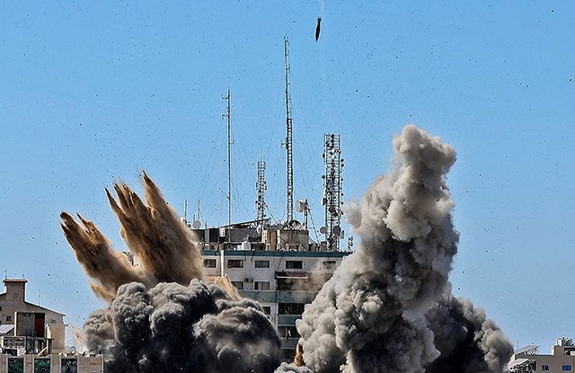 Smoke billows as an air bomb is dropped on the Jala Tower during an Israeli airstrike in Gaza city controlled by the Palestinian Hamas movement, on Saturday. Israeli air strikes pounded the Gaza Strip, killing 10 members of an extended family and demolishing a key media building, while Palestinian militants launched rockets in return amid violence in the West Bank. Israel's air force targeted the 13-floor Jala Tower housing Qatar-based Al Jazeera television and the Associated Press news agency (AFP photo)
