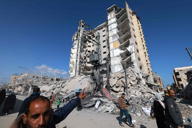 A Palestinian man points to a damaged building hit in an Israeli strike in Rafah, in the southern Gaza Strip on Sunday (AFP photo)