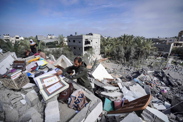  People salvage some items amid the rubble of the Palestinian Al Atrash family home, after it was destroyed in an Israeli strike in Deir  Balah in the central Gaza Strip on Wednesday (AFP photo)