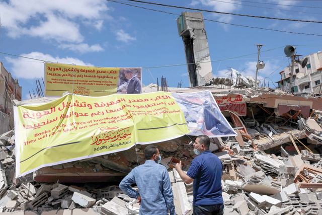 Palestinians look at the rubble of the Samir Mansour bookstore, a publishing house and bookshop which had the largest collection of English literature in Gaza, after it was destroyed by Israeli air strikes, in Gaza City, on Saturday (AFP photo)