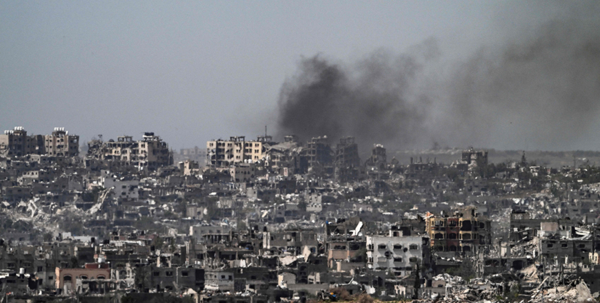 This photo taken from Israel’s southern border with the Gaza Strip shows smoke billowing behind destroyed buildings due to Israeli strikes on the besieged Palestinian territory on Tuesday (AFP photo)