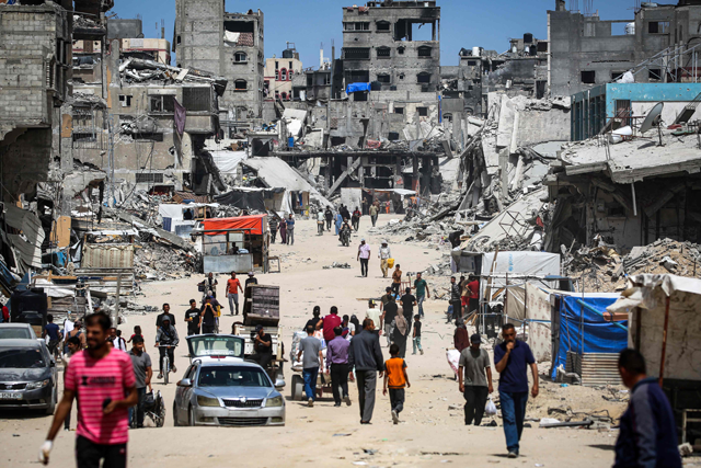 Displaced Palestinian walk along a devastated street in Khan Yunis in the southern Gaza Strip on Saturday (AFP photo)