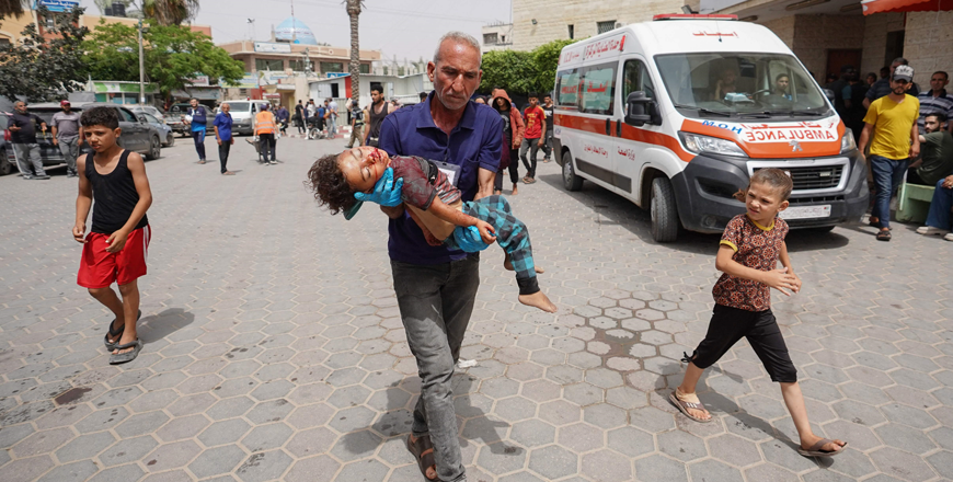 A man rushes Palestinian boy Khaled Abu Samaha to the Al Aqsa Martyrs Hospital in the central Gaza Strip after he was injured in Israeli bombardment on a house in Nuseirat city on Monday (AFP photo)