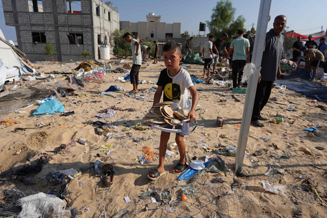 A Palestinian boy carries a bag with bread as people check the destruction in Deir el-balah in the central Gaza Strip, on Wednesday, following Israeli bombardment amid the ongoing Israeli war on Gaza (AFP photo)