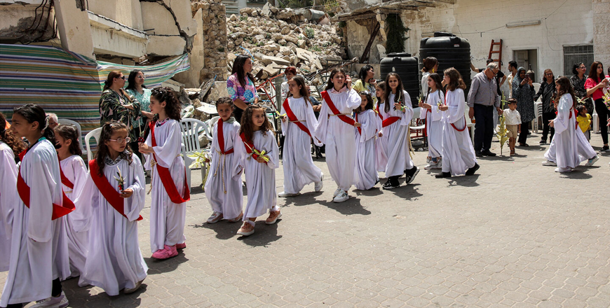 Child deaconesses walk past the rubble of a collapsed building in a procession during the Palm Sunday service outside the Greek Orthodox Church of St Porphyrius in Gaza City on April 28, 2024 (AFP photo)