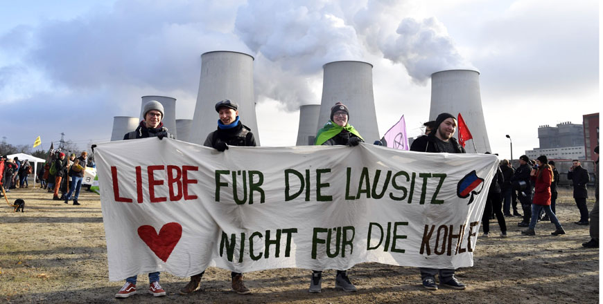Climate activists hold a placard reading ‘Love for Lausitz, not for the coal’ during a demonstration in front of the Jaenschwalde power plant in eastern Germany on Saturday (AFP photo)