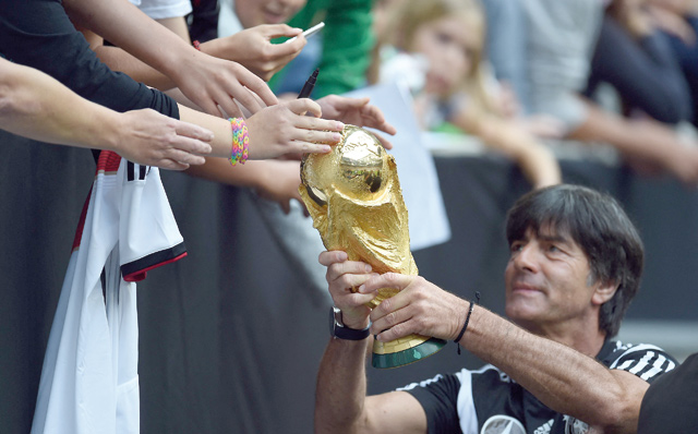 This file photo taken on September 1, 2014 shows Germany’s national football team head coach Joachim Loew holding the world cup trophy for fans to touch it during a public training session of the German national football team in Duesseldorf, western Germany (AFP photo)