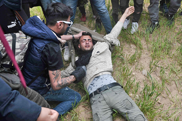 An injured man lies on the ground during clashes between migrants and Greek riot police outside of a refugee camp in Diavata, a west suburb of Thessaloniki, where migrants gather, on Saturday (AFP photo)