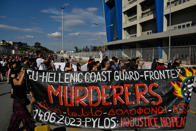 Protesters hold a banner in front of the Frontex and Hellenic Coastguard headquarters in the port of Piraeus near Athens, on Sunday (AFP photo)