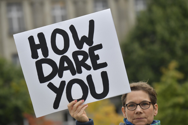 An environmentalist holds up a poster reading ‘How dare you’, quoting Swedish teenage climate activist Greta Thunberg, as she protests outside the German chancellery where is taking place the weekly cabinet meeting in Berlin, on Wednesday (AFP photo)
