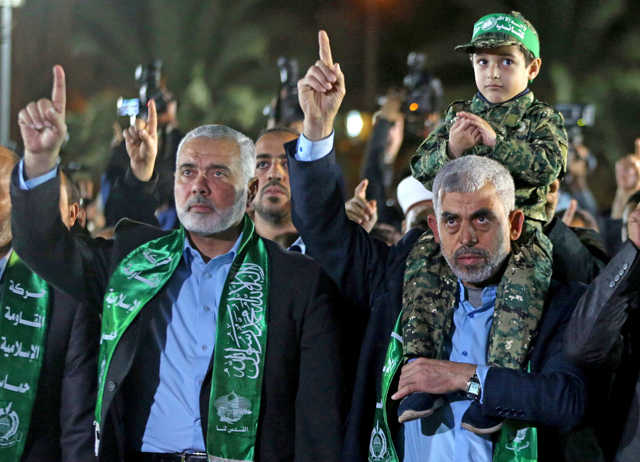 The son of senior Hamas militant Mazen Fuqaha sits on the shoulders of Hamas Gaza Chief Yahya Al Sinwar as Hamas leader Ismail Haniyeh (left) gestures during a memorial service for Fuqaha in Gaza City on March 27 (Reuters photo)