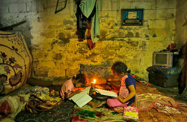This file photo taken on September 11 shows Palestinian children doing their homework during a power cut in an impoverished area in Gaza City (AFP photo)
