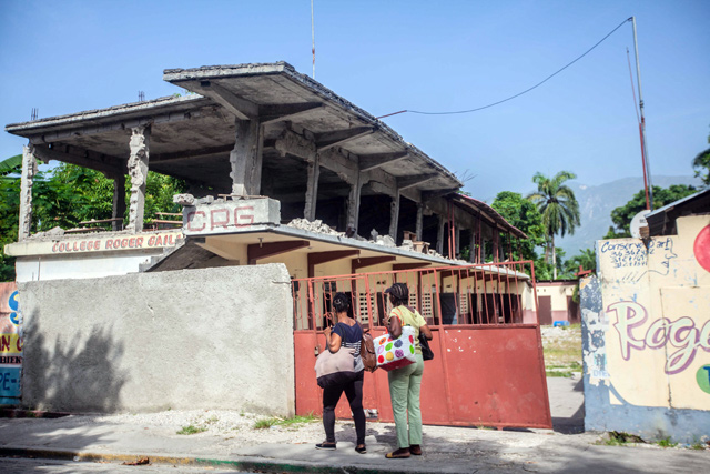 A worker carries chairs at the College de Mazenod damaged in the earthquake in Camp-Perrin, Haiti, on Tuesday (AFP photo)
