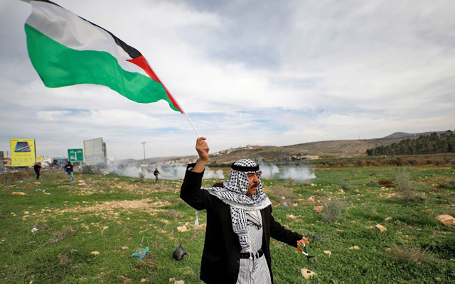 A demonstrator holds a Palestinian flag during clashes with Israeli troops at the Huwwara checkpoint near Nablus in the occupied West Bank on December 2, 2018 (Reuters photo)