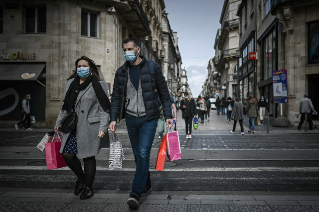A man and a woman carrying shopping bags cross a street located in the mandatory face mask zone to limit COVID-19 infections in Bordeaux on Wednesday as France is set to put tough new measures in place (AFP photo)