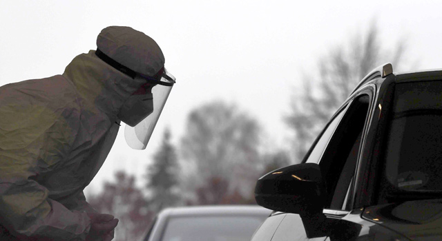A COVID-19 tester speaks with a car driver before the driver takes a smear himself in a car testing station in Erkheim, southern Germany, on Wednesday (AFP photo)