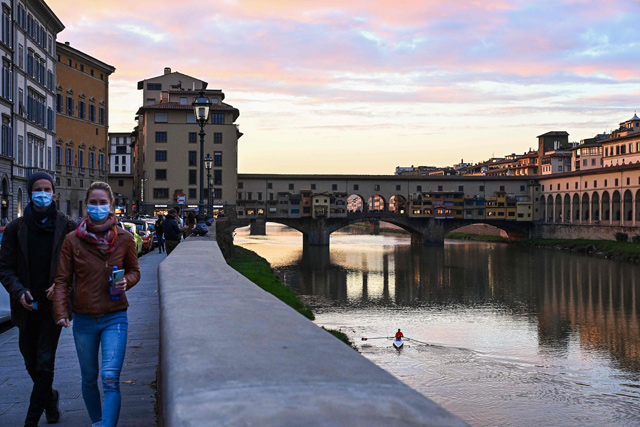 People walk at twilight along the Arno River near the Ponte Vecchio in downtown Florence, Tuscany, on Saturday (AFP photo)