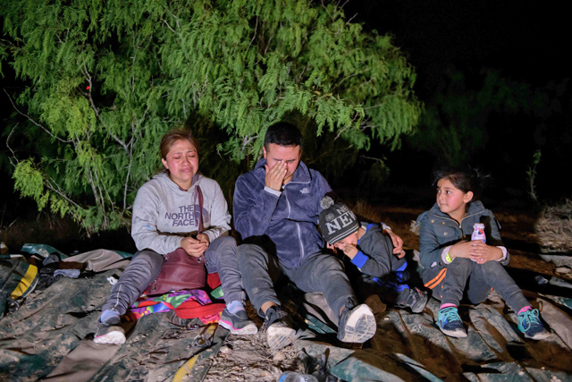Immigrants from Guatemala who arrived illegally across the Rio Grande River from Mexico rest on Saturday on the US side of the river bank following their crossing, before making their way towards a makeshift processing checkpoint in the border city of Roma (AFP photo)