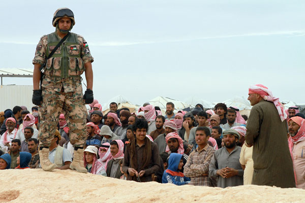 A soldier stands guard on the border with Syria as a crowd of refugees wait to be allowed to cross the border into safety on Wednesday (Photo by Hassan Tamimi)