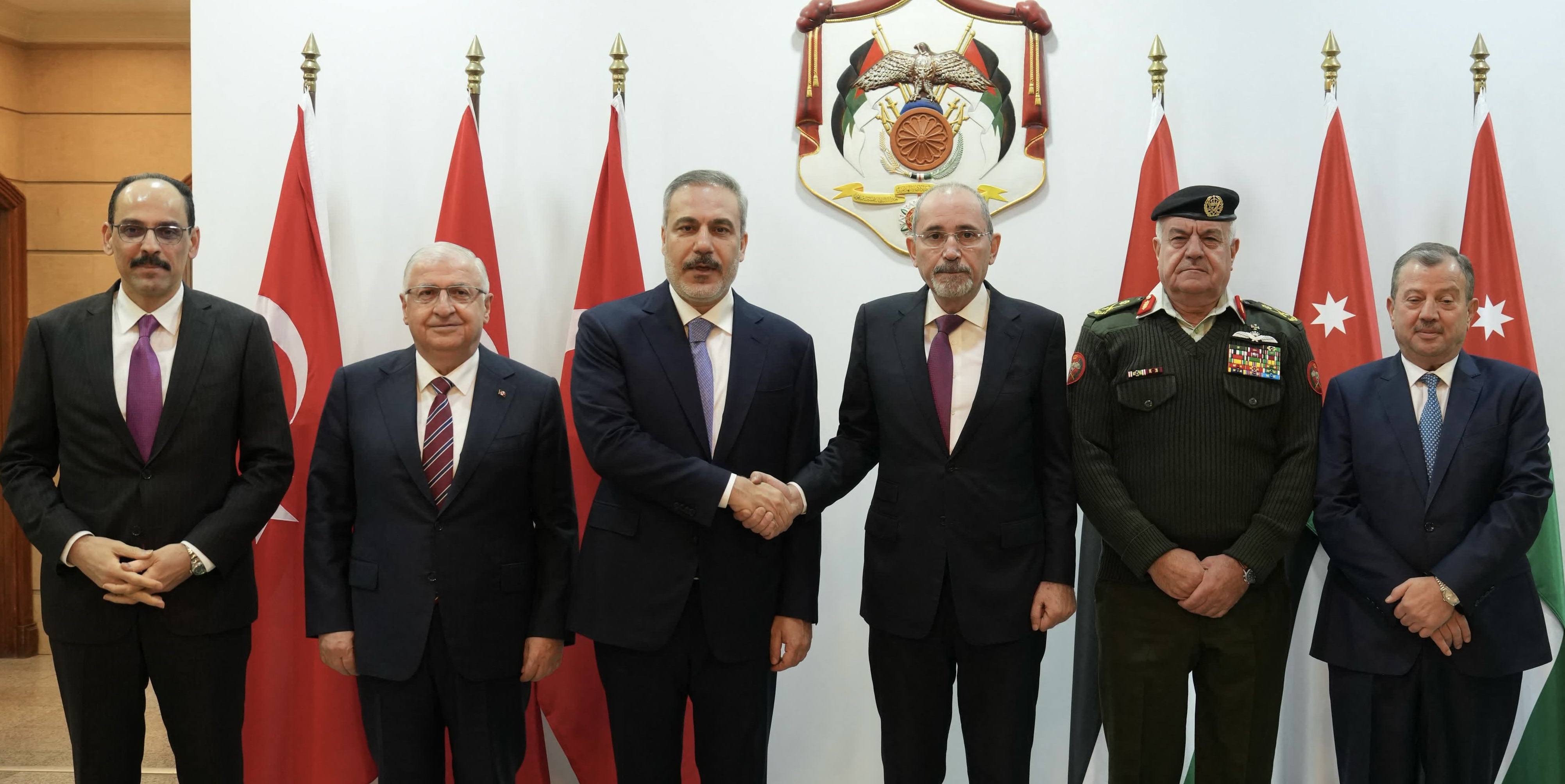 This handout picture released by the Foreign Ministry shows oreign Minister Ayman Safadi (C-R) shaking hands with his Turkish counterpart Hakan Fidan (C-L) during a meeting in the presence of the two countries' defense ministers, chiefs of staff and directors of intelligence services to discuss the situation in neighbouring Syria on March 9, 2025 in Amman (Photo courtesy of Foreign Ministry)