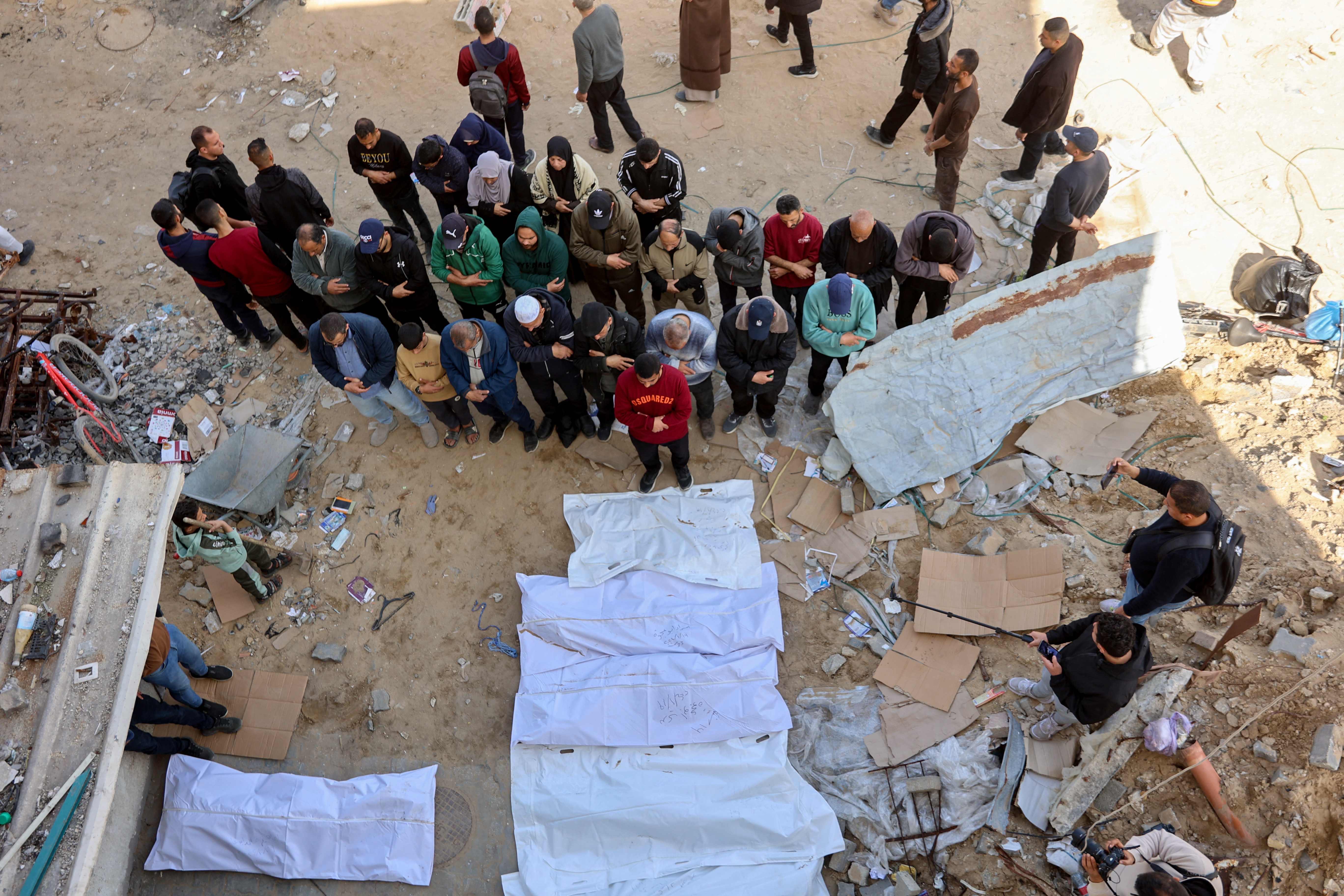 People pray over bodies after Palestinian civil defence workers uncovered corpses buried in the grounds of Al Shifa hospital in Gaza City, on March 13, 2025 (AFP photo)
