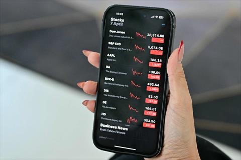A woman checks the stocks on her smartphone in Dubai on April 7, 2025 (AFP photo)