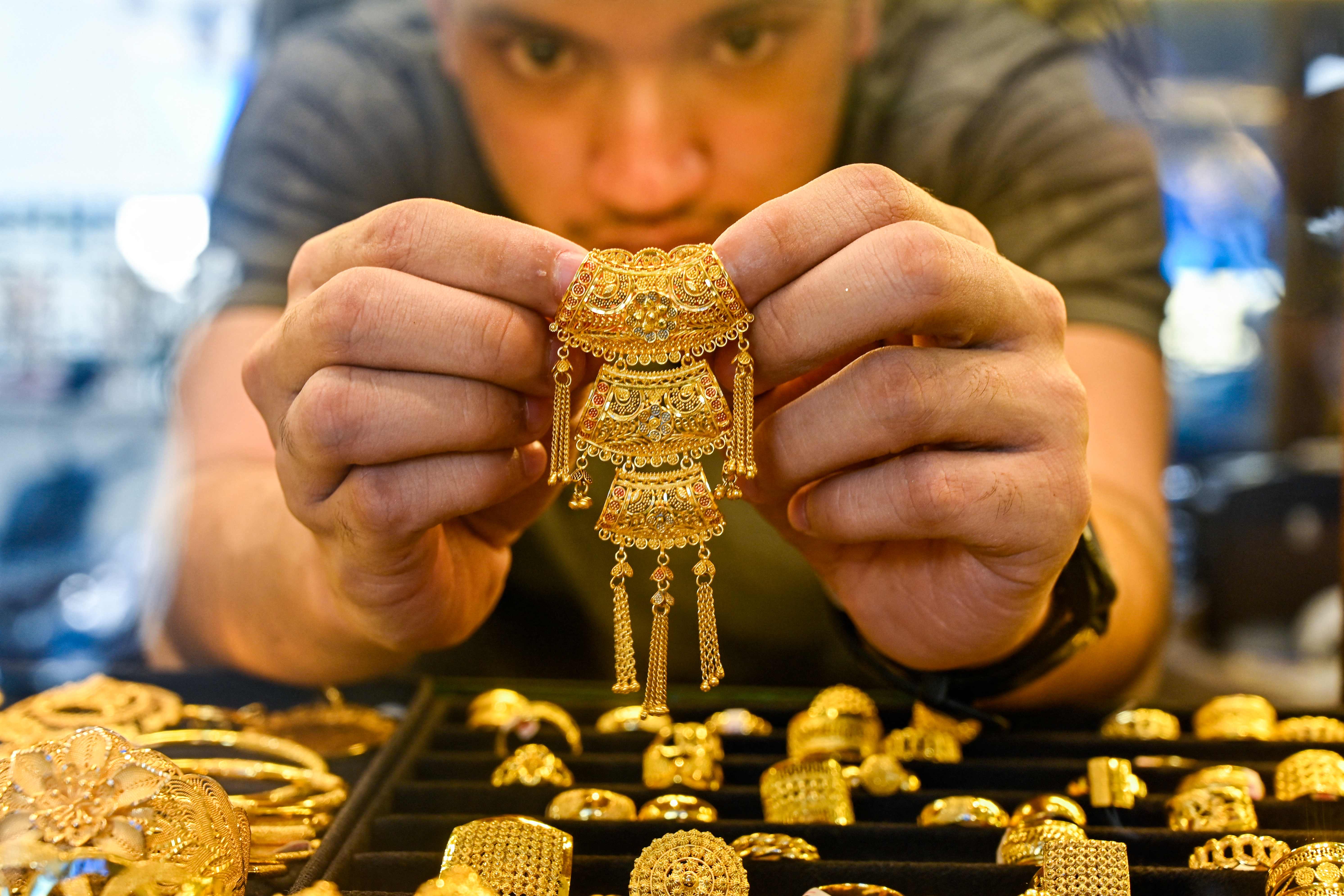 An employee holds a piece of gold jewellery at a market place in Banda Aceh on April 14, 2025. Asian stocks rose on April 14, as trade war fears were tempered by Donald Trump's announcement of tariff exemptions for electronics, though the dollar weakened and safe-haven gold hit a fresh record amid fears the relief would be short-lived (AFP photo)