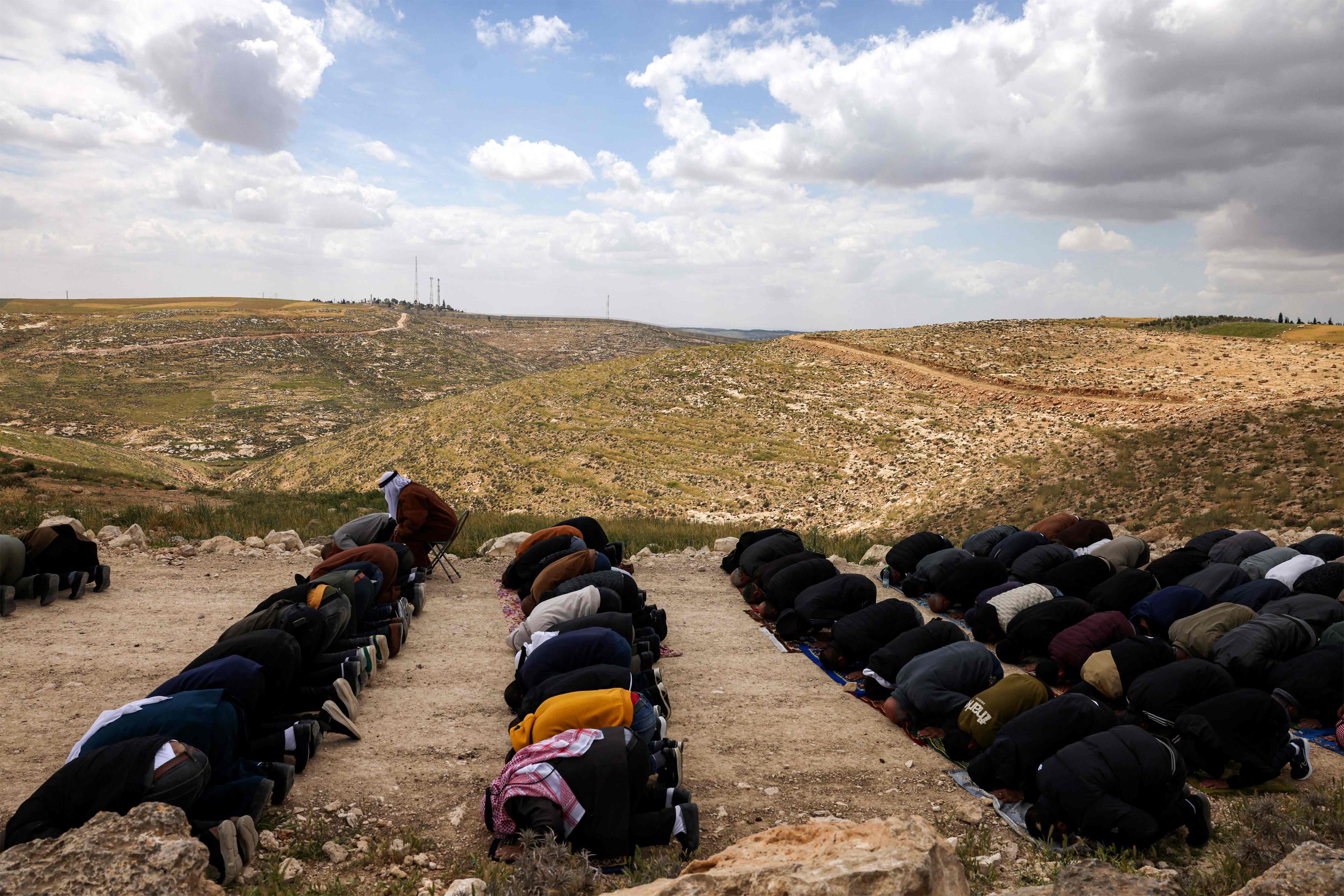 Palestinian men gather to perform the weekly Muslim Friday near lands confiscated by Israeli authorities from the Palestinian village of Dahriya, south of Hebron in the occupied West Bank, on April 11, 2025, currently being cleared to build a new road along Israel's controversial separation barrier  (AFP photo)