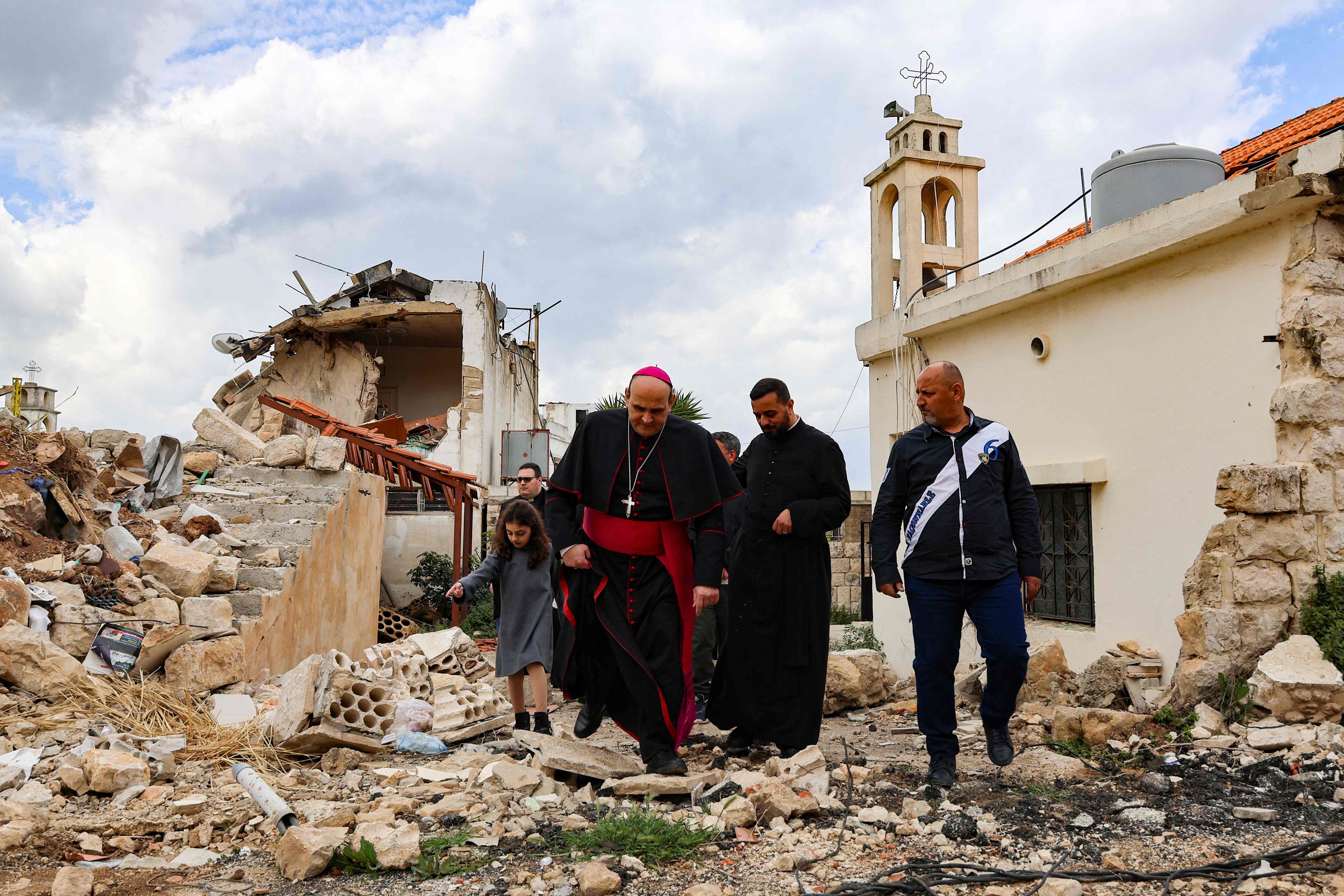 Papal envoy, Italian prelate of the Catholic Church Paolo Borgia walks with a Lebanese priest in front of a building destroyed by Israeli bombing in the recent war, during his visit to the southern Lebanese town of Khiam on Palm Sunday on April 13, 2025 (AFP photo)