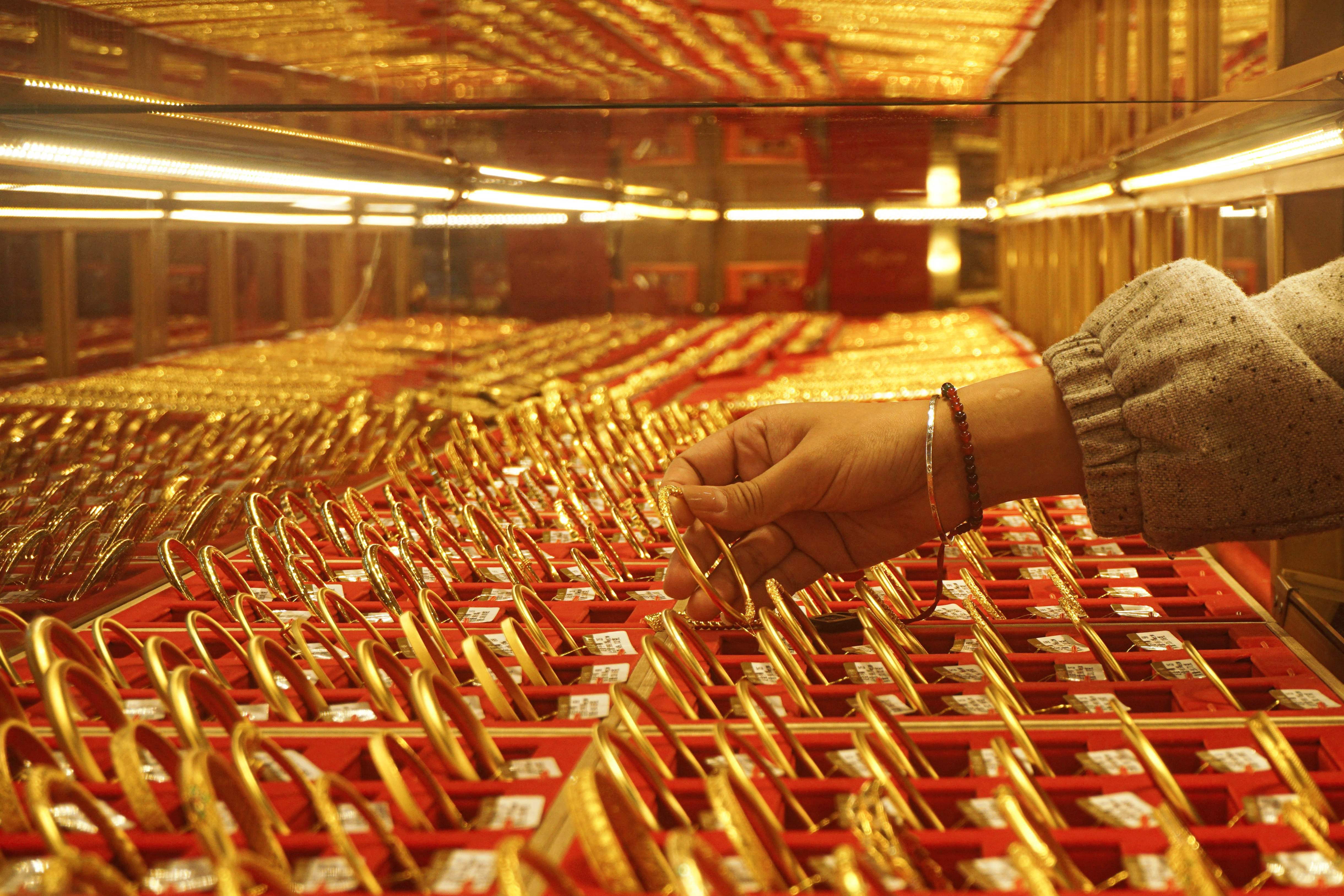 A shop assistant displays gold bangles for sale at a gold shop in Hangzhou, in eastern China's Zhejiang province on April 22, 2025 (AFP photo)