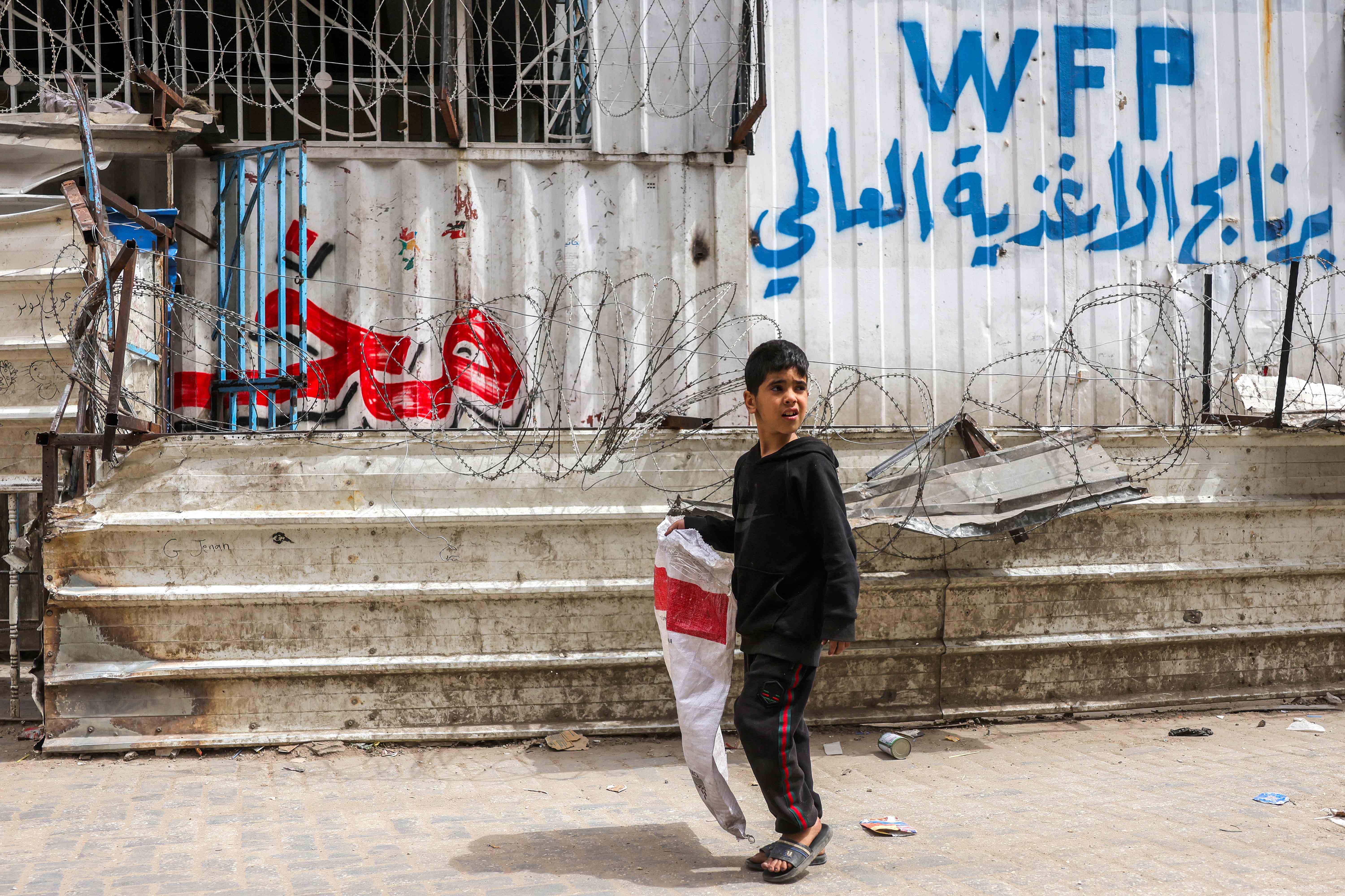 A boy walks with an empty sack past a closed-down bakery that ran out of flour in Gaza City on April 1, 2025 (AFP photo)