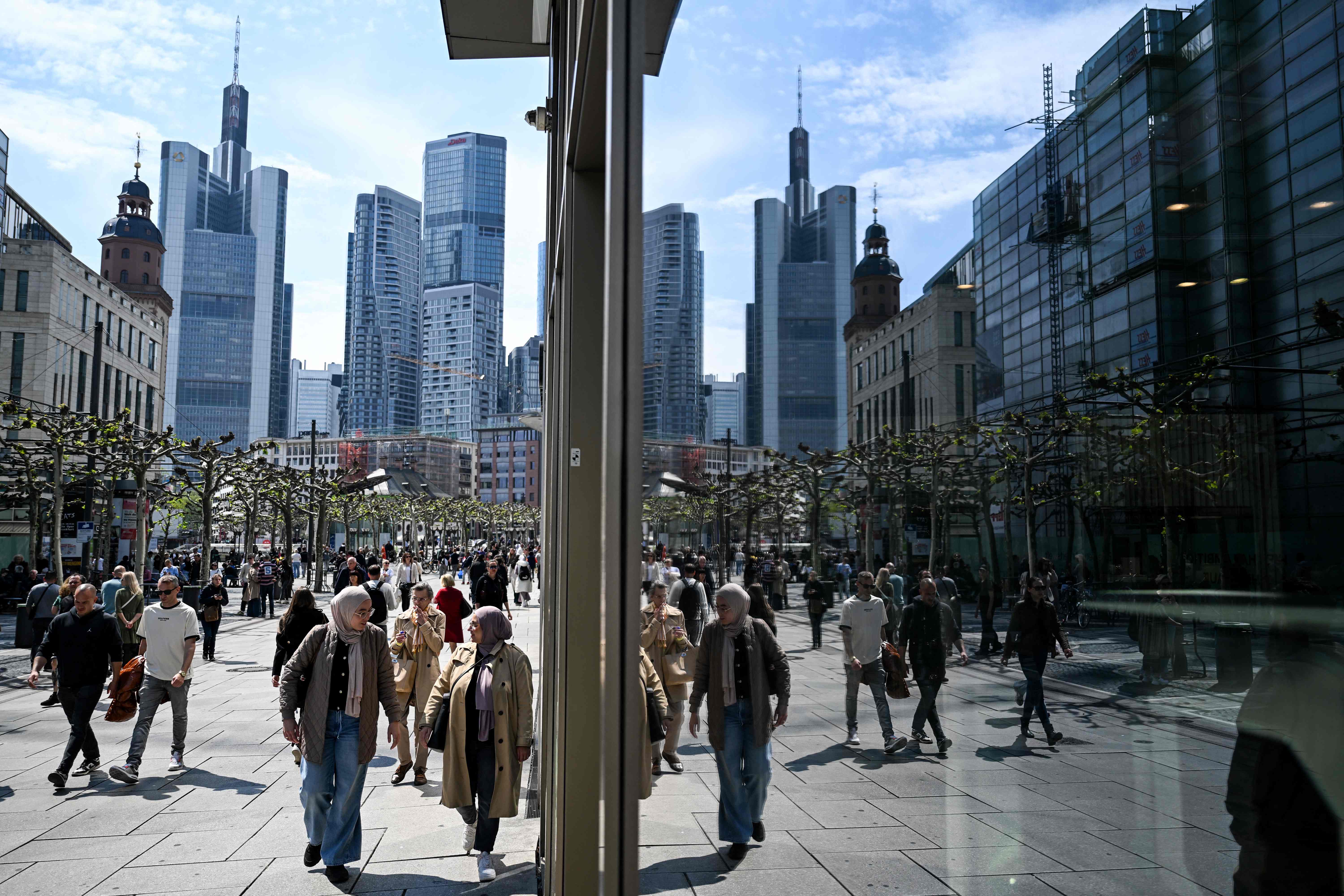 People walk on the main shopping Zeil street in front of the banking district skyline in Frankfurt am Main, western Germany, on April 23, 2025 (AFP photo)