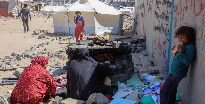 Palestinians bake bread in a makeshift outdoor oven near displacement tents in Gaza City on May 1, 2025 (AFP photo)