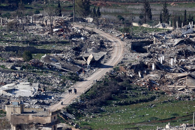 This picture taken from a position along Israel's northern border with Lebanon shows Lebanese residents inspecting the damage upon their return to the southern village of Mais al-Jabal, following the Israeli army's withdrawal on February 18, 2025