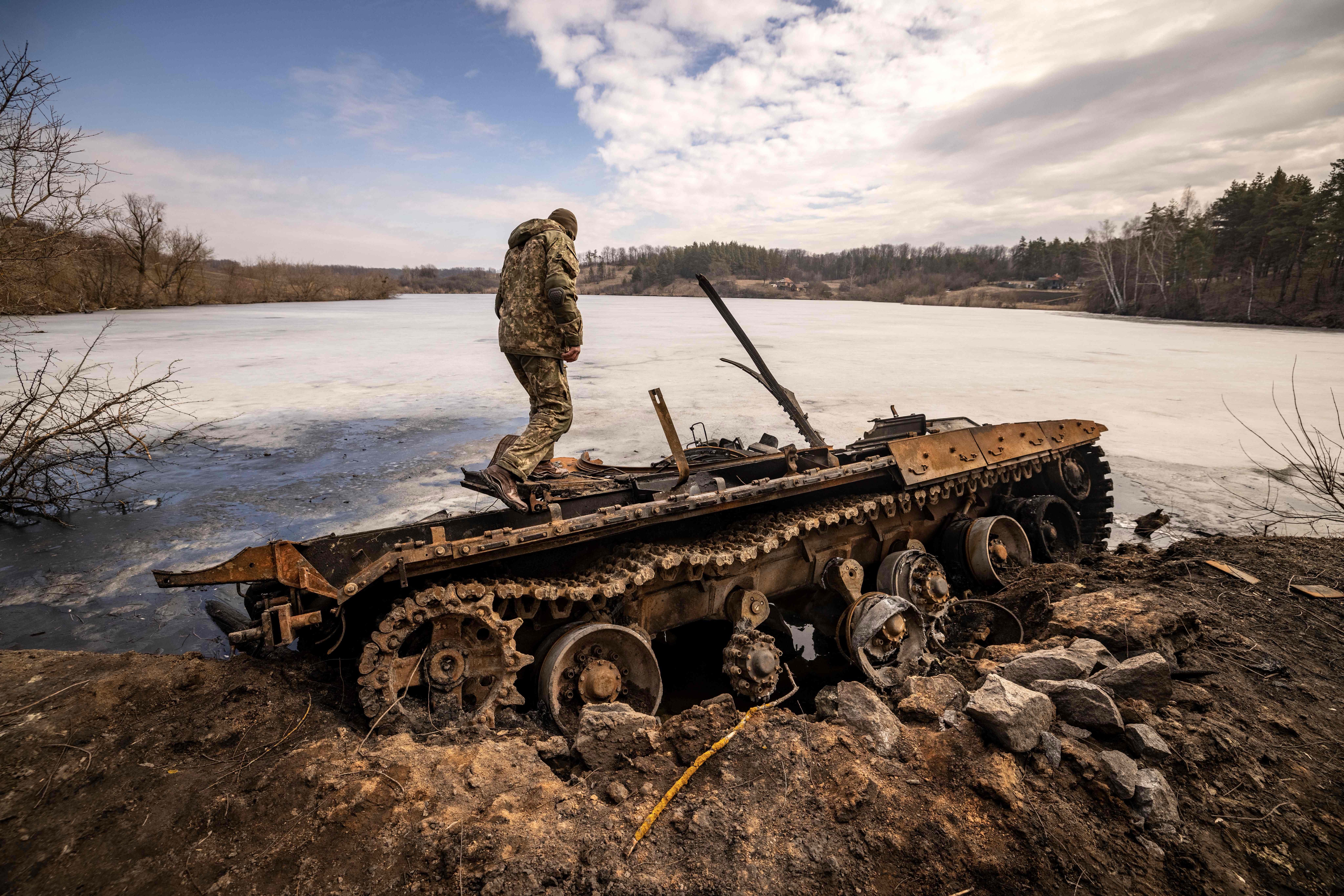  A Ukrainian serviceman stands near a destroyed Russian tank in the northeastern city of Trostyanets', on March 29, 2022.