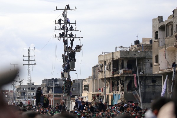 Palestinians climb over an electricity pole to get a glimpse of the release of three Israeli hostages as part of the seventh hostage-prisoner swap, in Nuseirat in the central Gaza Strip on February 22, 2025 (AFP photo)