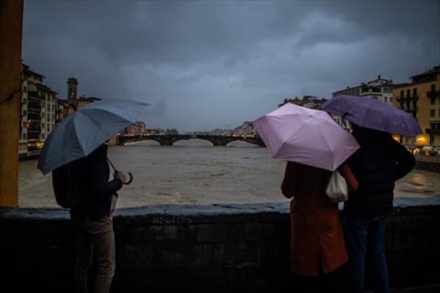 People watch the flow of the Arno River in Florence, on March 14, 2025. Heavy rain swelled rivers and flooded streets in an area near Florence with authorities issuing a red weather alert for the historic Italian city and its surroundings, urging residents to stay indoors (AFP photo)