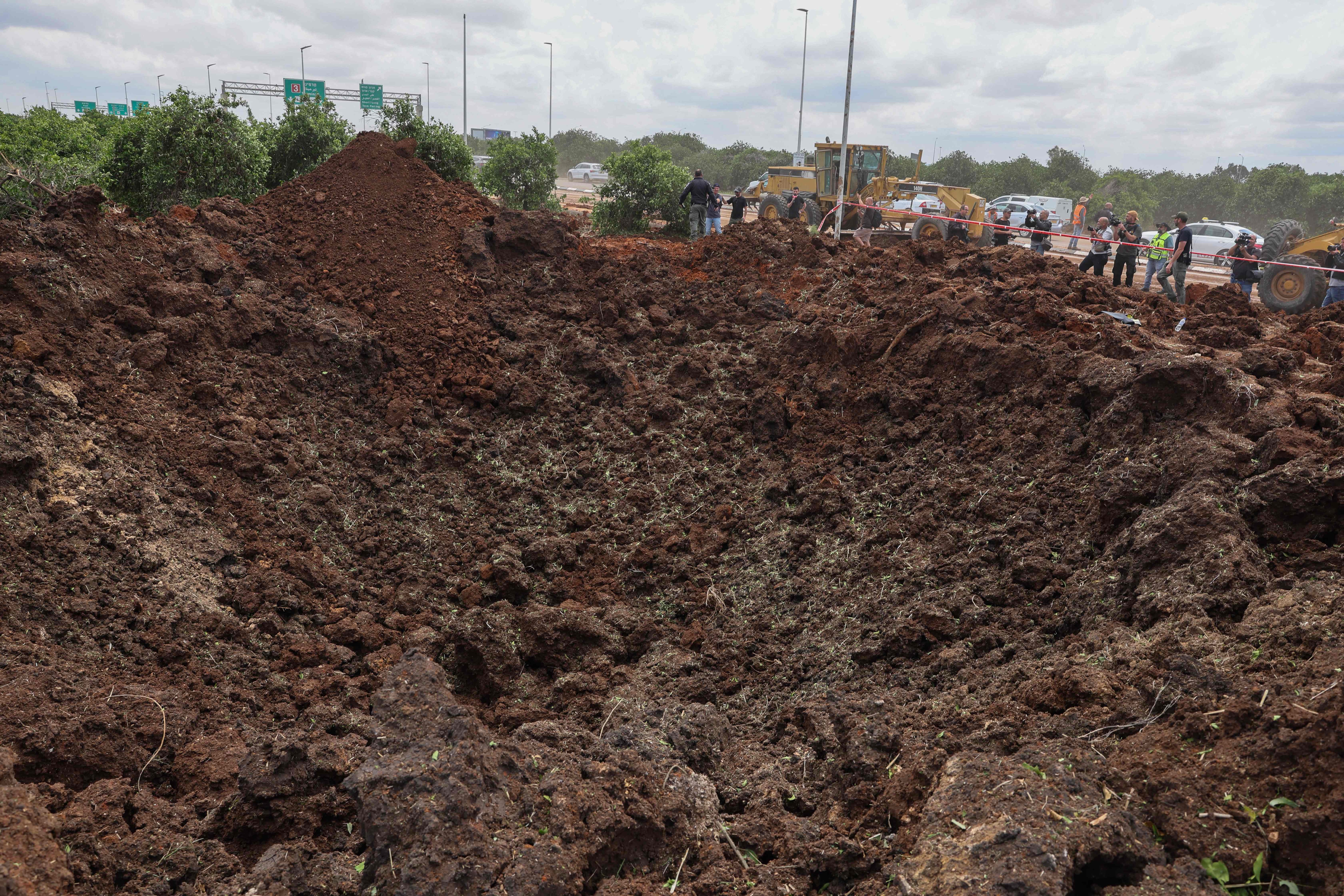 Members of Israeli security services inspect a crater near a road outside Israel's Ben Gurion airport after a missile launched from Yemen struck the area on May 4, 2025 (AFP photo)