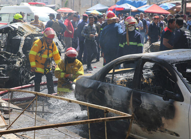 Firefighters try to extinguish fire as security forces cordon the area after a road-side parked car-bomb attack in Baghdad, Iraq, on Tuesday (Anadolu Agency photo)