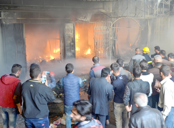 People inspect burned shops after mortar shells landed in a market in the city of Mosul, Iraq, on Sunday (Reuters photo)